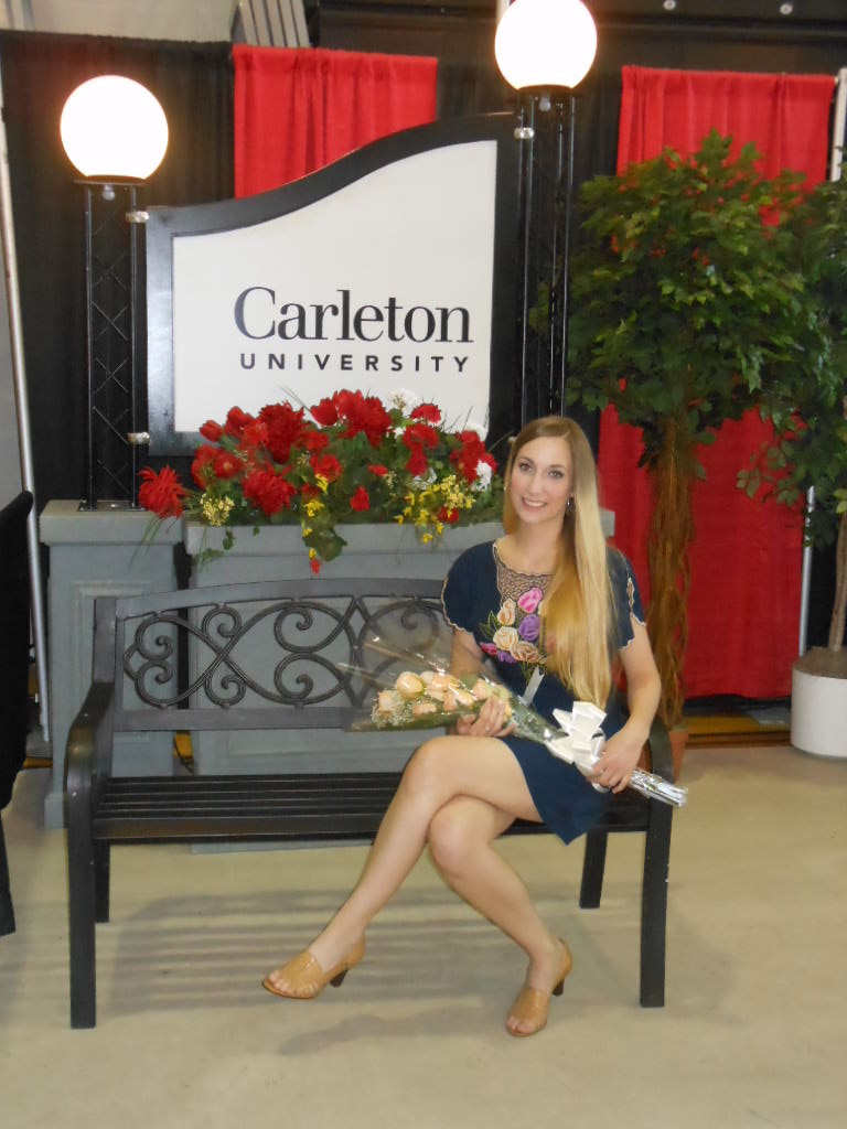 Deanna sits on a bench in a blue dress with a bouquet in her lap during her 2013 Carleton University graduation