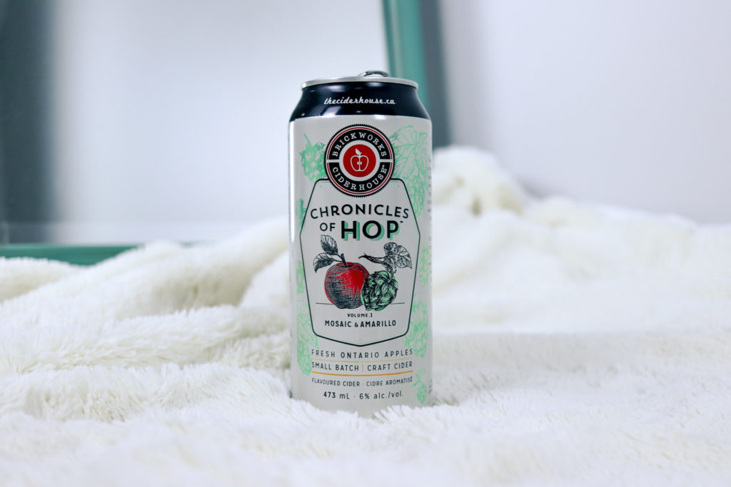 Detail photo of a Chronicles of Hop cider placed atop a soft, white blanket to highlight the Brickworks Ciderhouse beverage
